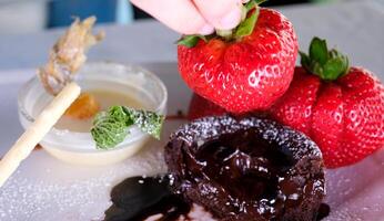 Chocolate fondant with strawberries, Chocolate fondant with strawberries and spoon on plate, isolated on white background, top view photo