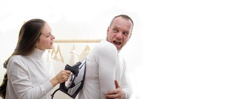 family scene in laundry room young brunette educates husband laundry ironing family in white golfs on white background positive emotions joy prank fooling around fun smile photo