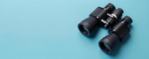 Binoculars on blue copy space background photo