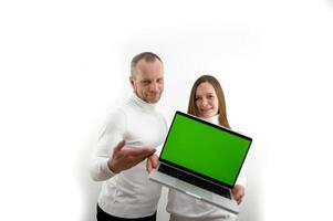 modern mobile phone Use this new app. Cheerful couple point to smartphone and laptop with blank screen recommend mobile app, advertise website mockup for design chroma key green screen selective focus photo