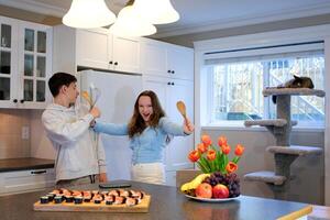 boy girl in kitchen playing fighting dancing having fun spending time together fooling around eating sushi alone at home no parents first date children playing brother and sister classmates friends photo