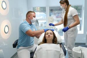 Group of students in dental clinic learn watching dental treatment with a microscope photo