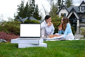 rápido Fresco Pizza entrega juventud joven hermano y hermana sentado en picnic comiendo Pizza en antecedentes en primer plano ordenador portátil con blanco pantalla soportes en blanco cajas con entrega verano márketing foto