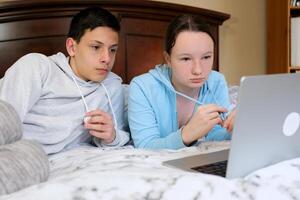 Ambitious Young Couple Working on Laptop in Bed Young couple signing documents together while sitting on the couch at home photo