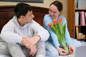 first date to give flowers the girl is shy the boy Gave bouquet watching movie flowers in vase of water girl hugs them very happy laughs to look suddenly at friend feeling teenagers relationship photo