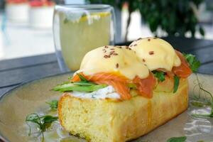 Typical but trendy breakfast close up shot, knife cut poached egg on top of egg Benedict meal, we see yellow liquid yolk inside. Stylish food with salmon and hollandaise sauce, served at trendy cafe photo