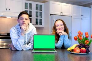 adolescentes cerca ordenador portátil con verde pantalla chromakey en cocina publicidad comida golosinas Cocinando espectáculo formación en línea fiesta día apagado chico y niña Mira dentro marco hermosa caras frutas y flores foto