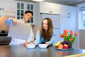 young Caucasian couple having breakfast at home. A woman pours milk for her husband into a bowl of cereal. photo