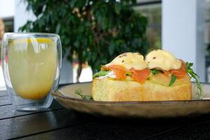 Typical but trendy breakfast close up shot, knife cut poached egg on top of egg Benedict meal, we see yellow liquid yolk inside. Stylish food with salmon and hollandaise sauce, served at trendy cafe photo