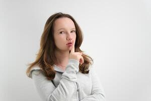 un joven mujer con largo pelo aislado en un blanco fondo, Cállate Sin palabras mantener silencio. conmocionado sorprendido dama fuera índice dedo labios pedir no compartir confidencial novedad foto