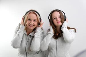 Mother and daughter listening to music on white background photo