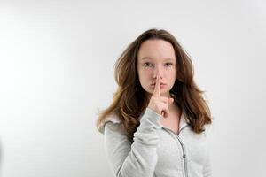 Young woman says ssshhh to maintain silence on a white background photo