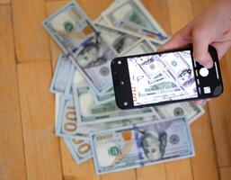 Smart Phone Extends Fanned 100 Dollar Bills photo