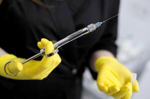 Black clothes long flowing hair white cabinet office dentistry Young girl woman with syringe in hand anaesthesia yellow gloves doctor nurse Doctor, girl, syringe injection photo