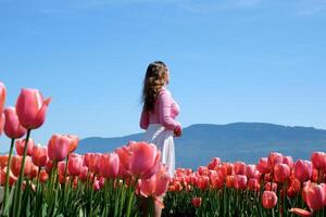 colección de videos y fotos dónde un niña en un blanco falda camina mediante campo con tulipanes azul antecedentes cielo montañas brillante floración campos adolescente joven mujer caminar al aire libre belleza cuidados personales