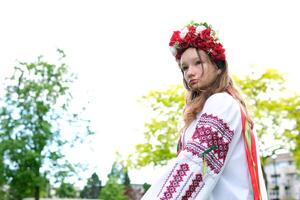 beautiful Ukrainian young woman tender girl in a large red wreath of bright pink white red flowers braiding ribbons in hair wind tenderness cleanliness peace in Ukraine Peacetime people Real life photo