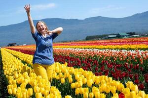 adult woman in field of tulips clothes blue yellow like flag of Ukraine joy happiness in mountains blooming Yellow flowers Freedom freshness air yellow pants blue blouse fair-haired ordinary female photo