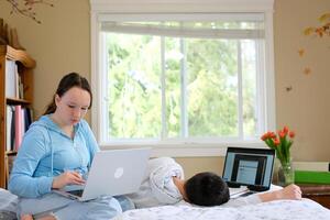 teenagers sit at computers do their homework online study and are not tired of studying go to bed fall asleep One works the other sleeps no desire to study eyes hurt need to rest photo