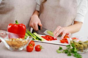 Couple preparing a meal cut bell pepper Close up cropped image of cutting board and couple cutting vegetables in the kitchen together, preparing food meal at home. Vegetarian healthy food photo