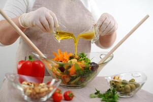 salad in glass bowl from two jugs stream oil sauce with mustard and honey ingredients front tablecloth olives tomatoes red peppers carrots Bright colors are not recognizable people fresh vegetables photo