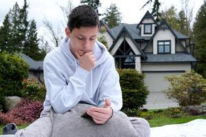 un Adolescente chico se sienta en el teléfono yendo a su mano en el jardín en almohadas pedidos alguna cosa artilugio Los telefonos comunicación educación en línea en línea colegio redes y juegos para juventud y niños foto