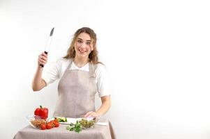 Young caucasian woman holding a knife and cutting vegetables photo