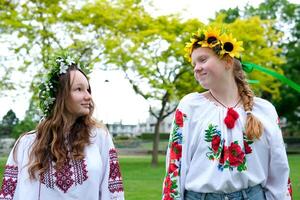 Midsummer. Two girls in Slavic clothes talking while sitting by the fire photo