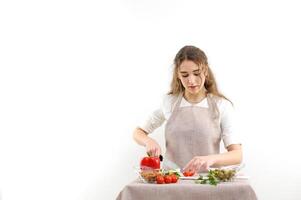 Beautiful young woman preparing vegetable salad in the kitchen. Healthy food. Vegan salad. Diet. Diet concept. Healthy lifestyle. Cook at home. Prepare food. Cutting ingredients on the table photo