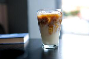 A large transparent glass filled with cold summer drink with ice cubes is photographed on a gray, isolated background, photo for the menu