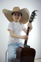 con confianza sostiene un guitarra en su manos en sombrero obras de teatro un guitarra en un blanco antecedentes descanso relajación un musical instrumento Tienda un ropa Tienda para niños sombreros jardín de infancia hora a colegio foto