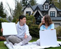 teenagers boy and girl sitting on a picnic with white boxes empty space for advertising text pizza cake on a plaid sportswear thumb up look at each other love for food joy approval tasty picnic photo