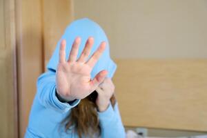 I said stop it. put hood over eyes of teenager Blurred portrait of young lady extending hand forward saying no enough to abuse family violence abortion. close up raised in prohibiting gesture photo