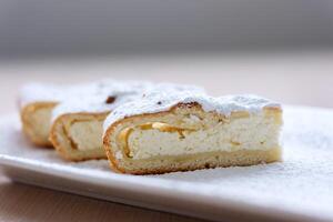 cheesecake curd strudel sliced on white plate sprinkled with powdered sugar dough is separated from curd creating drawing place for text advertising benefits of cooking show recipes restaurant serving photo