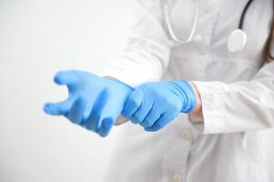 cerca arriba científico manos poniendo en nitrilo azul látex guantes en bata de laboratorio vistiendo nitrilo guantes, haciendo experimentos en laboratorio foto