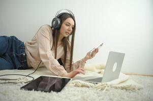 una estudiante sonriente usa auriculares inalámbricos para estudiar en línea con un profesor de skype, una joven feliz aprende el idioma escucha una conferencia mira un seminario web escribe notas mira una laptop sentada en un café, educación distante foto