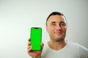 Positive millennial man showing huge brand new smartphone with empty screen and thumb up over white studio background, mockup, panorama with copy space, newest mobile app concept photo