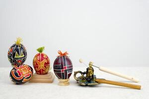 special devices for coloring eggs four eggs of different colors red yellow black with tufts of thread on a white background space for text postcard easter eggs holiday celebration of easter photo