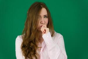 Concept close-up portrait of a pretty girl, a young woman with long beautiful brown hair and in a black jacket on a green background. In the studio in different poses showing emotions. photo