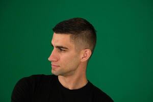 Close up profile view of young handsome man isolated against emotions of a handsome man guy on a green background chromakey close-up dark hair young man photo