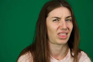 facial asco diferente emociones de un joven niña en un verde antecedentes chromakey hermosa facial caracteristicas real personas rosado camiseta blanco desollado europeo foto