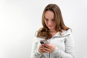 Portrait of tense concentrated female teenager with very long brown hair playing game on her cell phone being winner gesturing in joy over white background. Concept of emotions photo