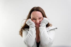 A young woman standing in front of a white wall and making a surprise gesture photo