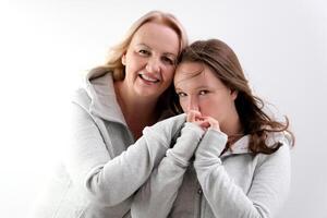 love of daughter and mother hugging kisses tenderness girl kisses her mother's hands mother hugs kisses her daughter on the cheek two women on a light background a lot of tenderness and joy of love photo