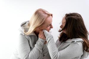 love of daughter and mother hugging kisses tenderness girl kisses her mother's hands mother hugs kisses her daughter on the cheek two women on a light background a lot of tenderness and joy of love photo