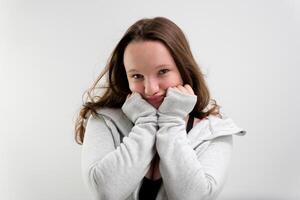 hug yourself young girl posing in front of camera teenager preparing stories and reels smile showing tenderness on white background photo shoot shrug look to side at photographer alone in frame