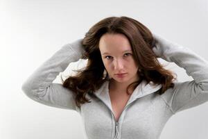 put on a sports outfit, a young teenage girl is preparing for sports, a black top and a gray sports jacket in the studio, beauty, grooming, straighten her hair, button up her jacket photo