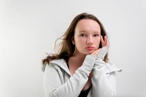 thinking girl put hand to chin and does not understand the situation thinks rolled her eyes upward pouting her lips on a white background teenager in the studio incomprehensible situation photo