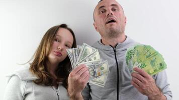 father and daughter a lot of money in their hands joy success dollars euro 100 dollar bill wave money like a fan look into the frame make faces confidence success big win purchase gift photo