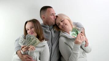 happy rich family dollars and euros in hands of mom daughters dad father hugs smiling happy waving money like fan on white background a lot of money luck travel in games kissing relatives on the head photo