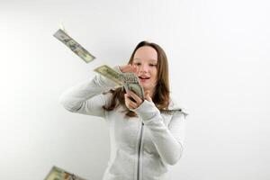 Arrogant wealthy girl scattering dollars with proud haughty expression, boasting rich life, throwing around cash, squandering wasting money carelessly. indoor studio shot isolated on blue background photo